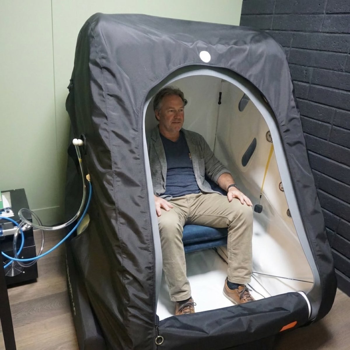 A client sitting in the open hyperbaric chamber, looking away from the camera