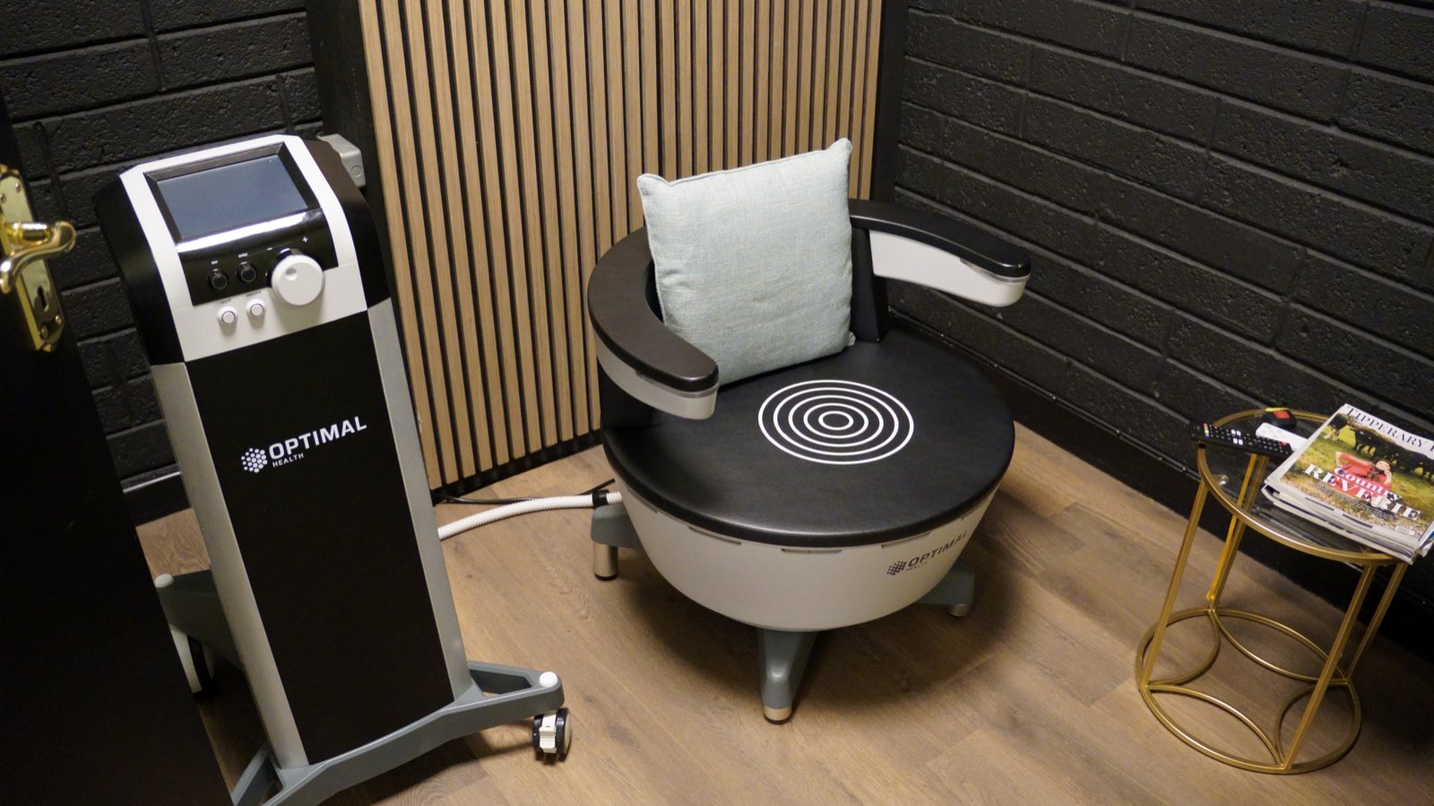 The HIFEM chair and its console, empty, a cushion on the seat and a side table alongside