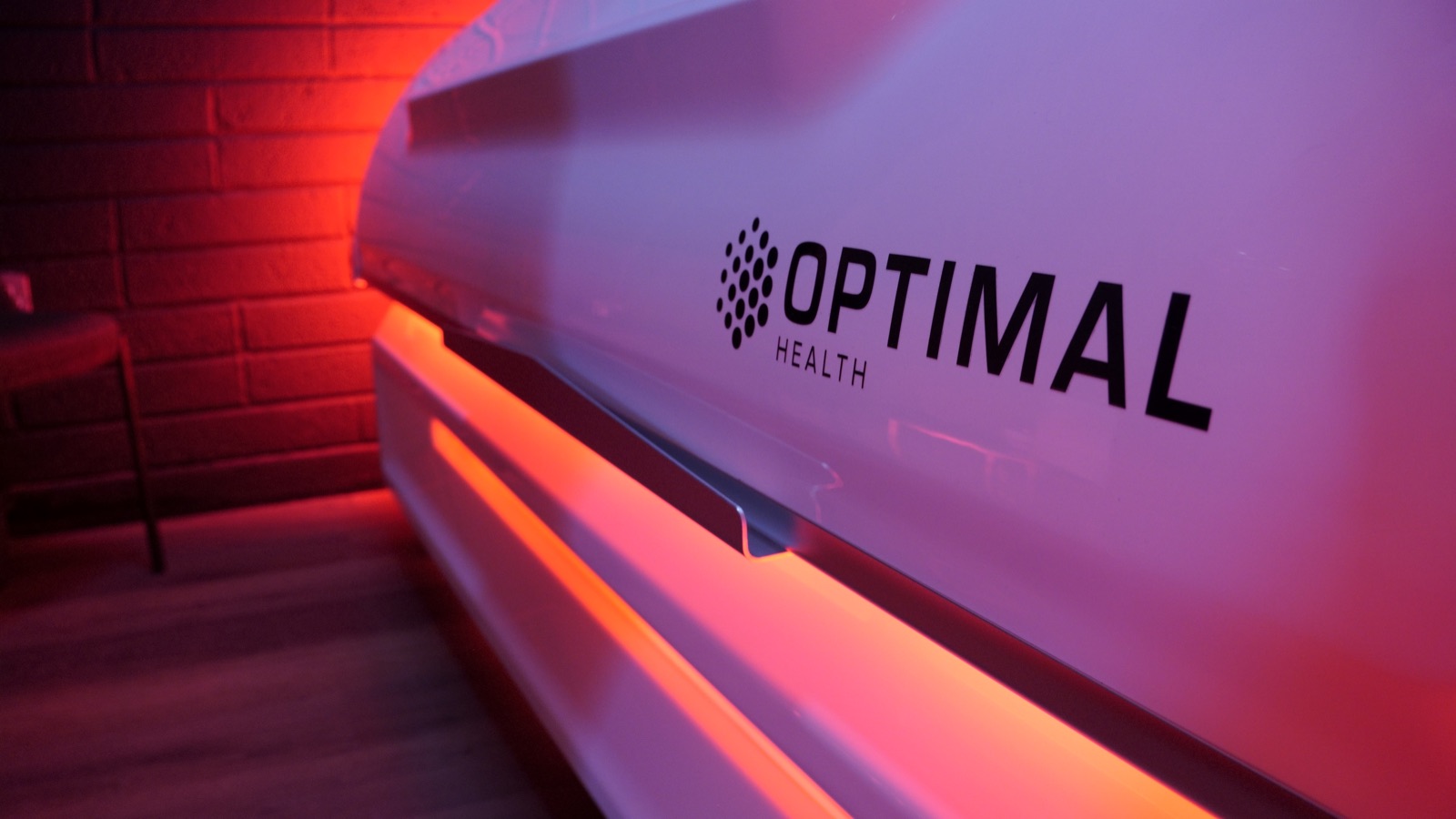 Close on the Optimal Health name set into the bed's shell, under a red wash