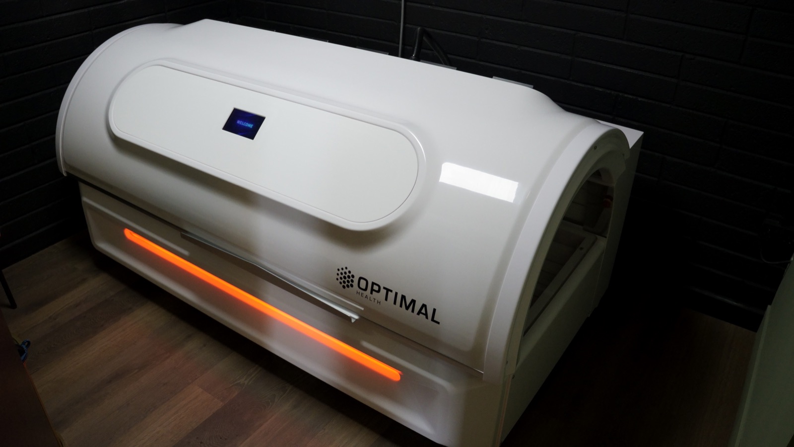 The infrared bed closed and waiting in the treatment room, its orange strip lit