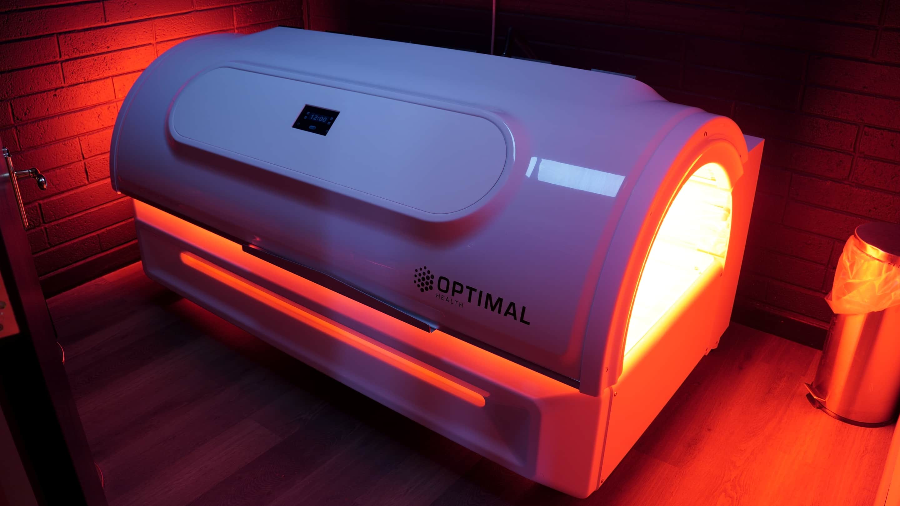 The infrared bed running, its red light spilling across the brick wall behind it