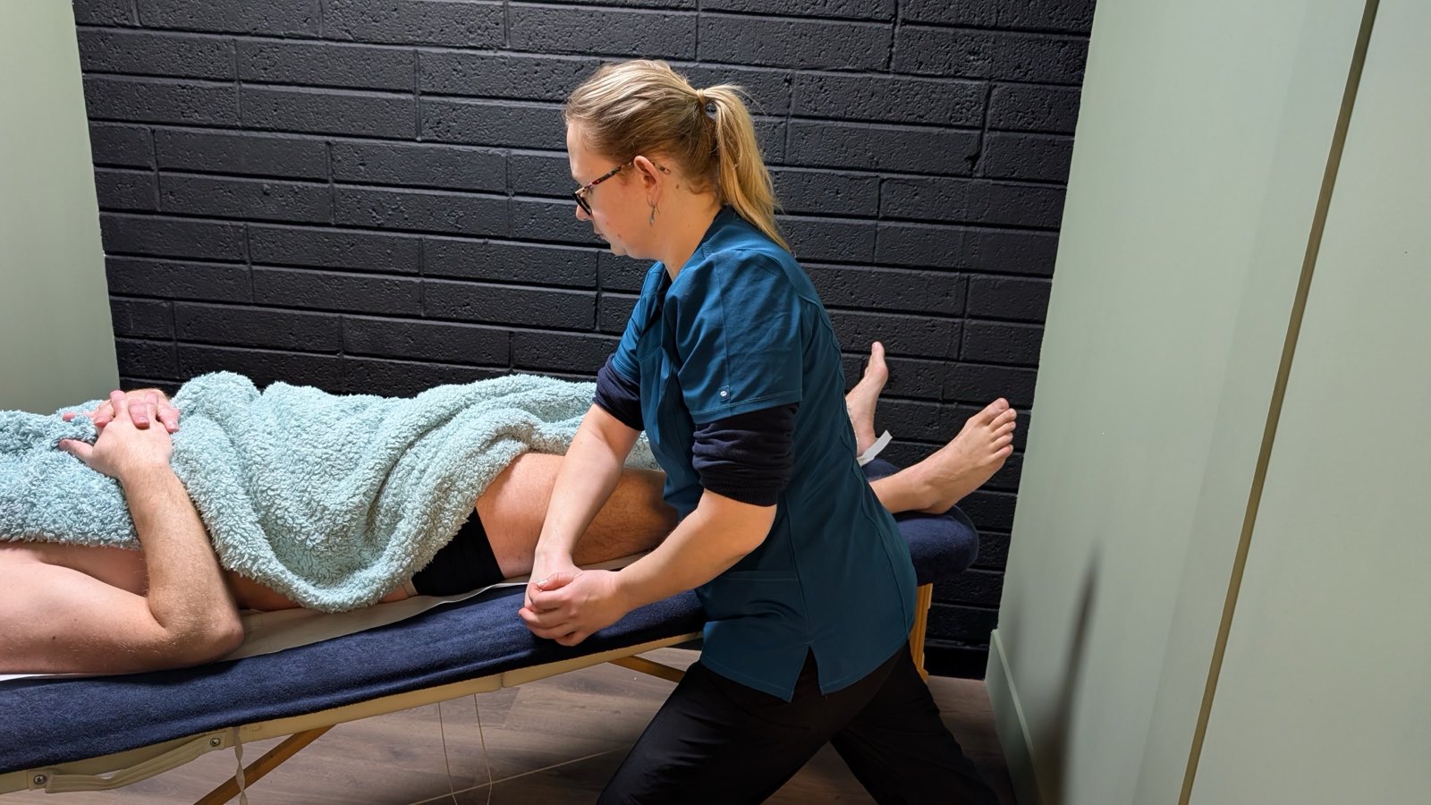 A therapist stretching a client's leg on the treatment couch